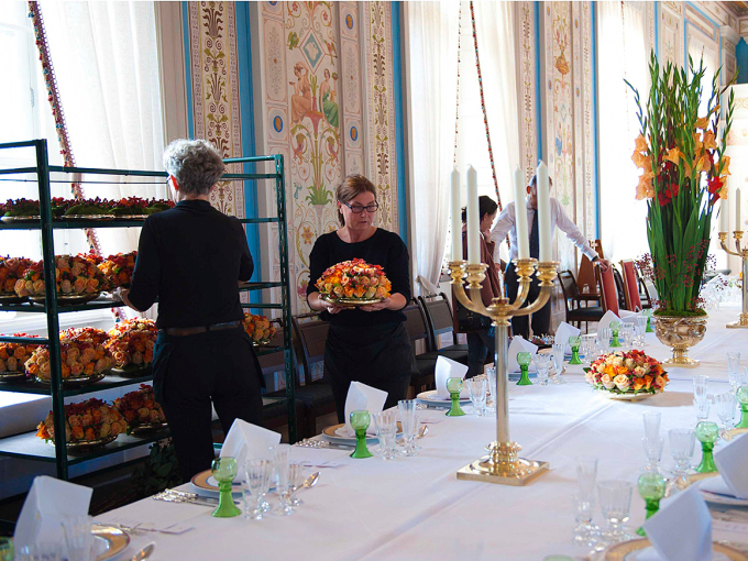 Blomsterdekorasjoner kommer på plass på bordene til en gallamiddag. Foto: Mona Nordøy